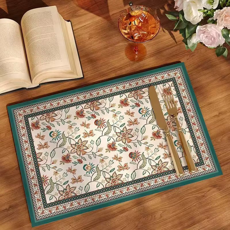 A rectangular provincial botanical placemat with a floral pattern, featuring a teal border and cream center, table setting inspiration. Provincial botanical placemat. teal border and cream centre placemat. oil proof and water proof and heat resistant. 35cm*40cm dimension , 1.7mm thickness