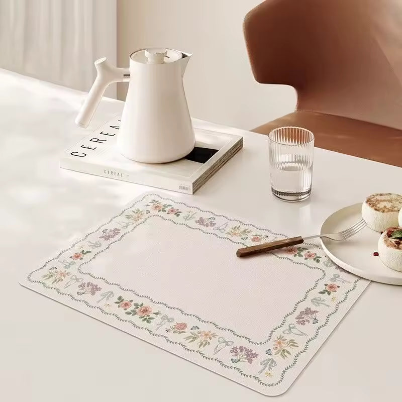 A rectangular white placemat with a delicate floral border pattern with a clean beige background.