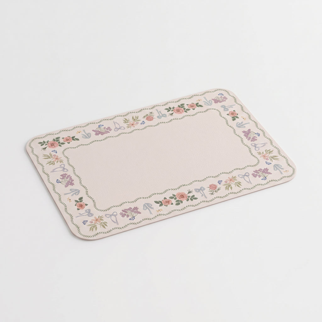 A rectangular placemat with rounded corners, featuring a delicate floral border in soft pastel shades of pink, purple, green, and blue, set against a clean beige background.